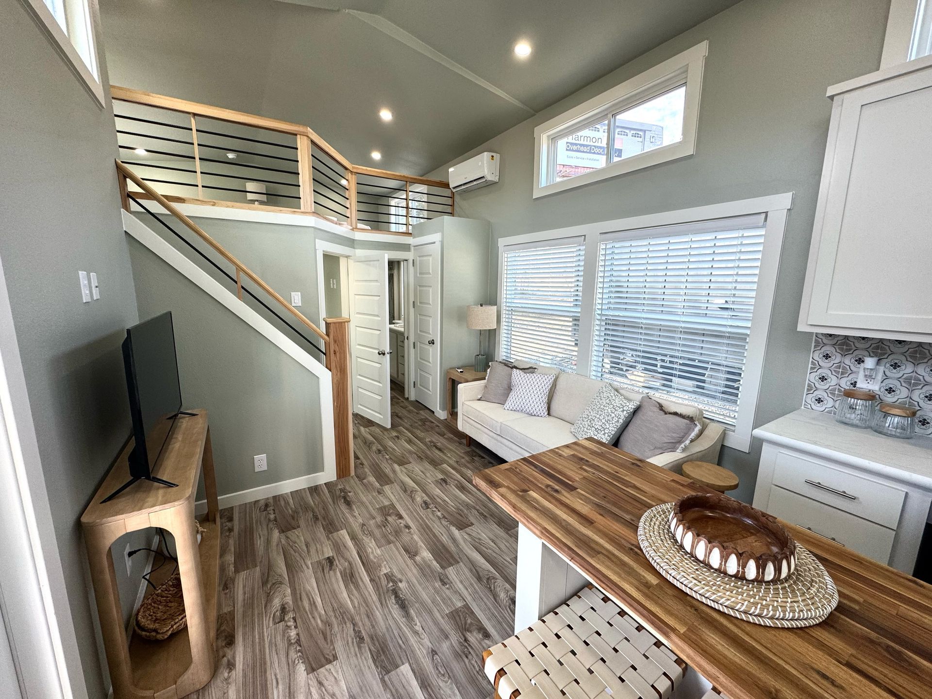Tiny house interior with a loft, sofa, kitchen, and dining area.