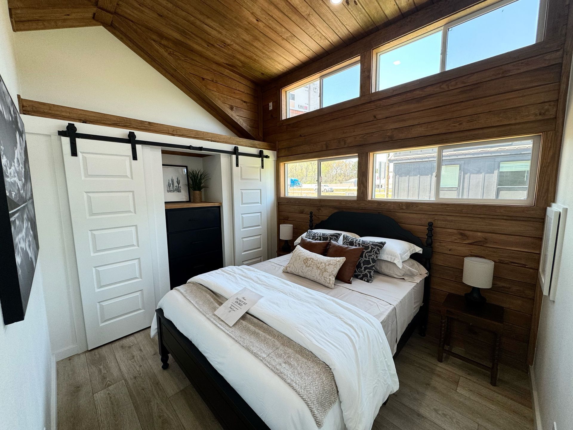 Cozy bedroom with wooden walls, a bed, and closet with sliding doors.