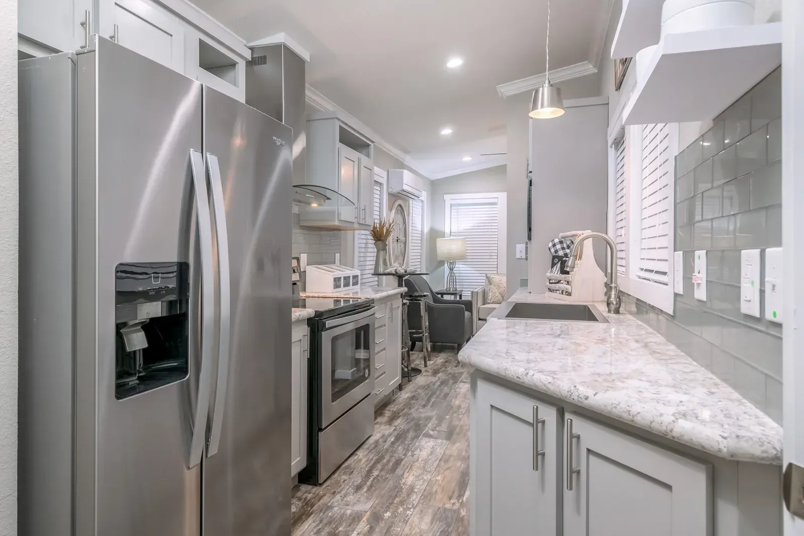 Modern kitchen with stainless steel appliances, light gray cabinets, and a white countertop.