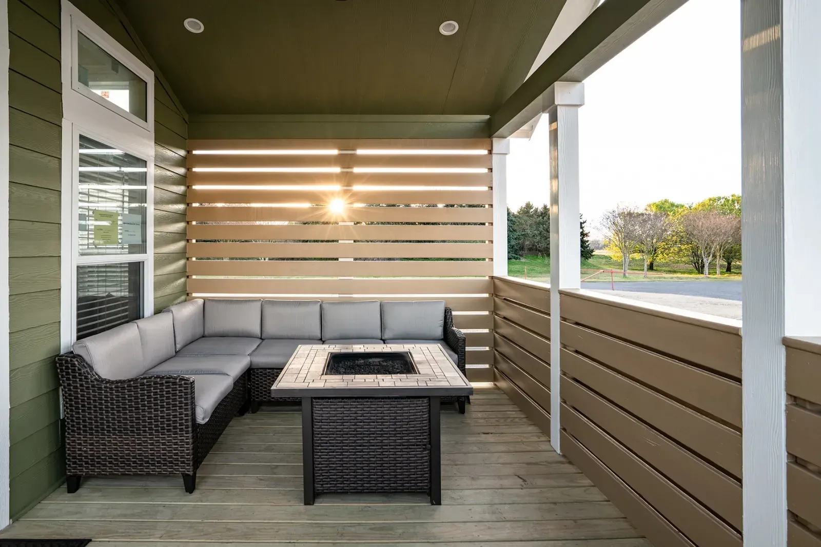 Outdoor patio with sectional sofa, fire pit, and horizontal wood slat walls.