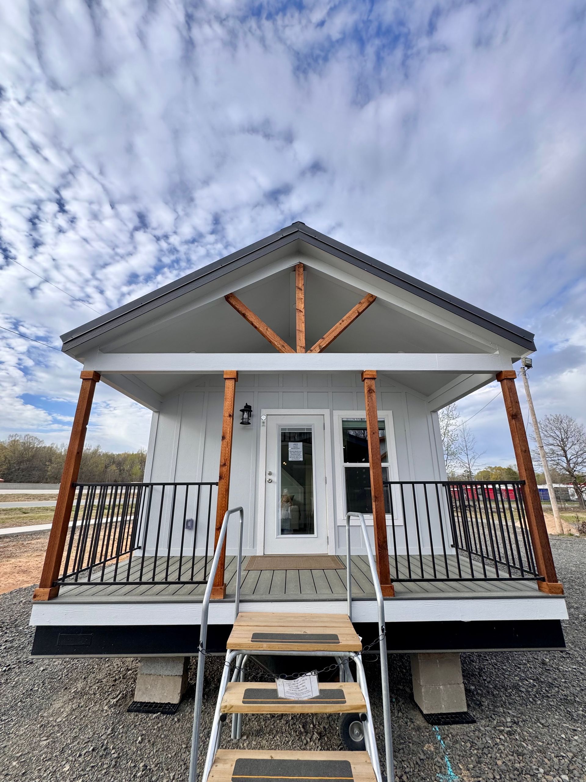 A small white house with a porch and stairs is being built.