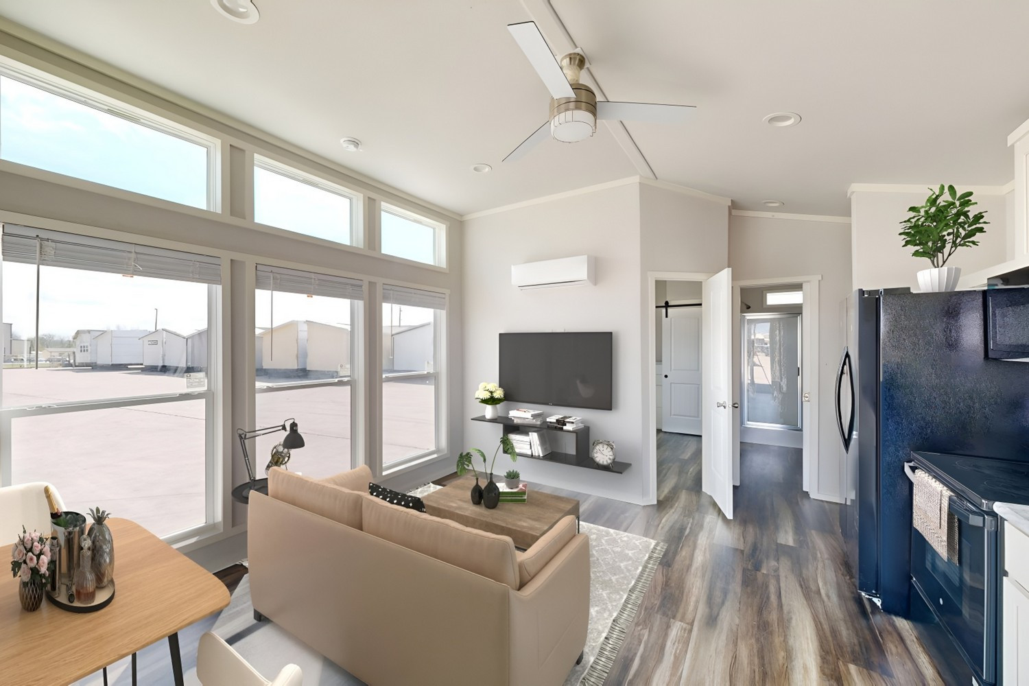 Modern living room with large windows, light sofa, TV, and open doorway.