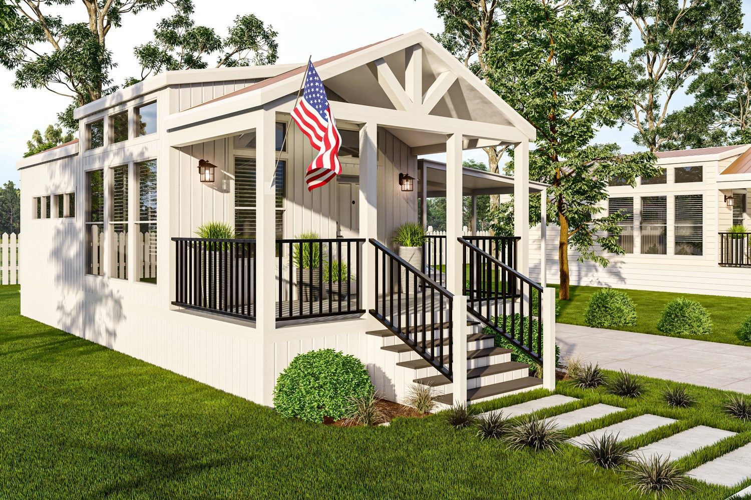 White tiny house with porch and American flag, set in a grassy yard.