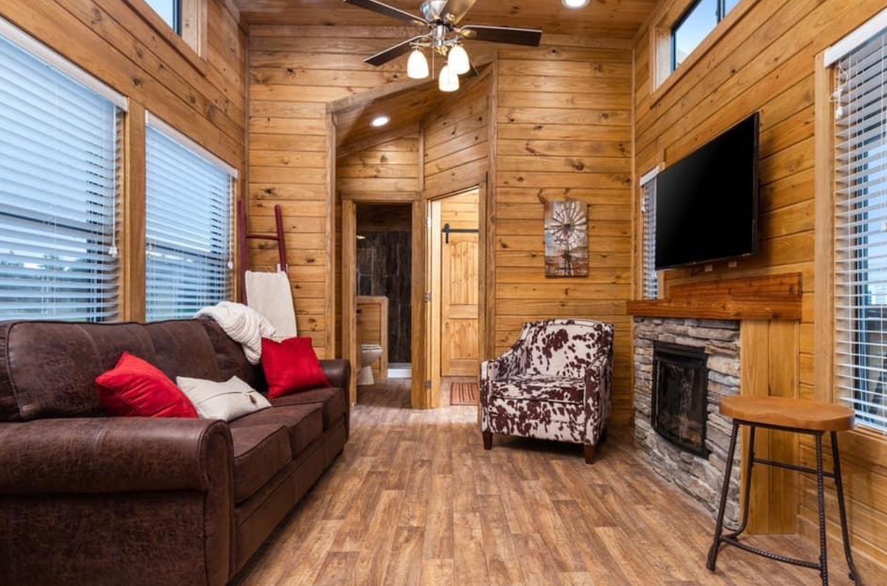 A living room with a couch , chair , fireplace and television.