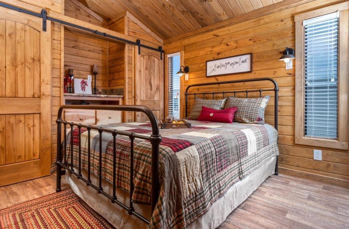 A bedroom in a log cabin with a king size bed and a sliding barn door.
