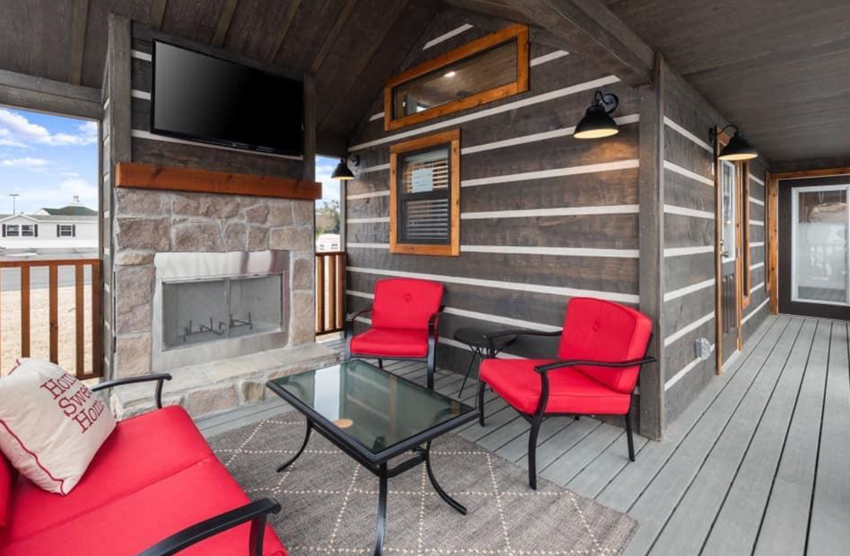 There is a fireplace on the porch of a log cabin.