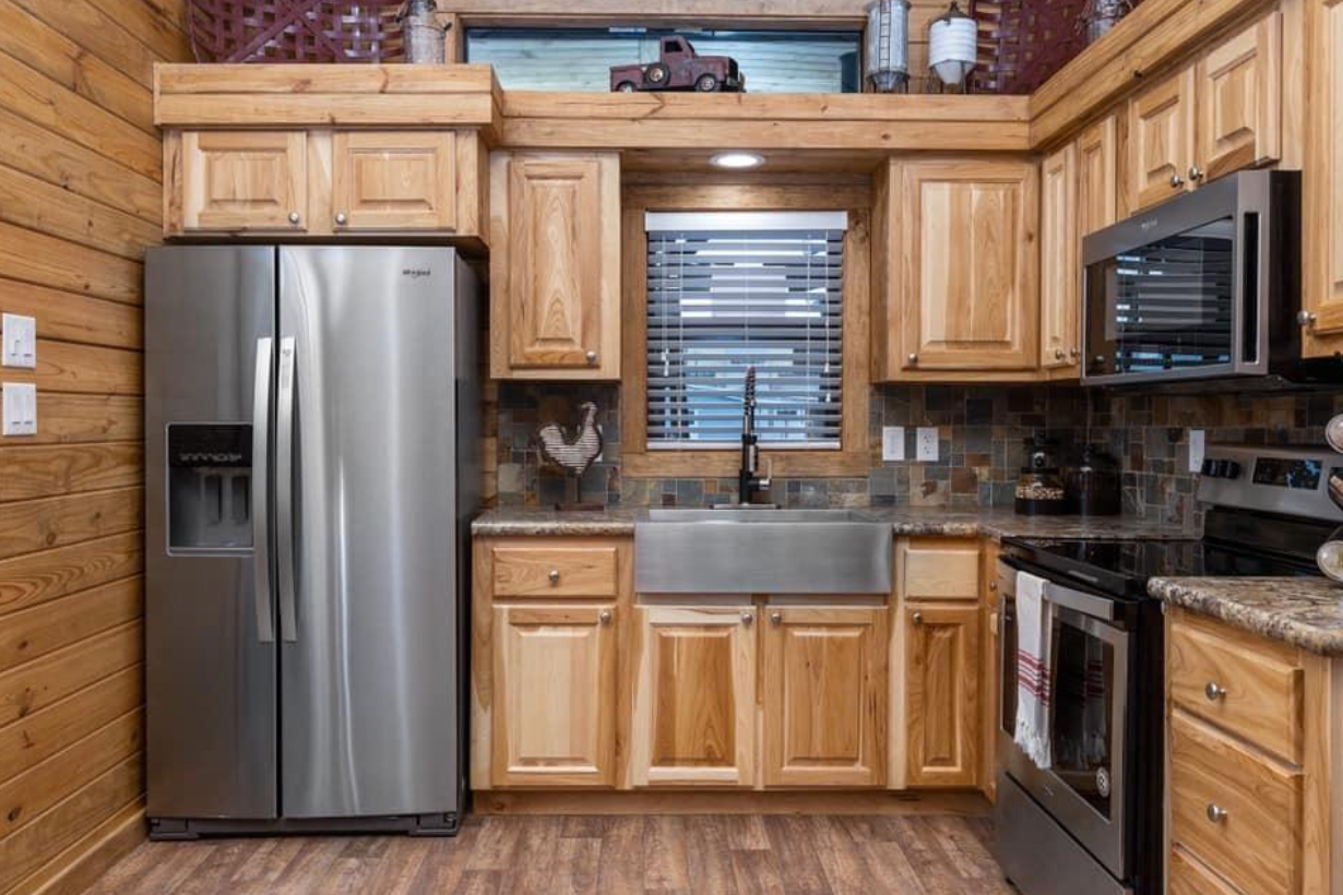 A kitchen in a log cabin with stainless steel appliances and wooden cabinets.