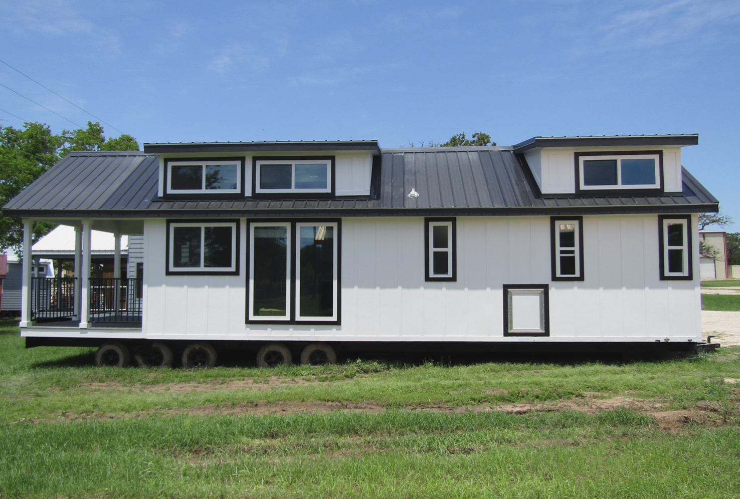 A white house with a black roof is sitting on top of a lush green field.