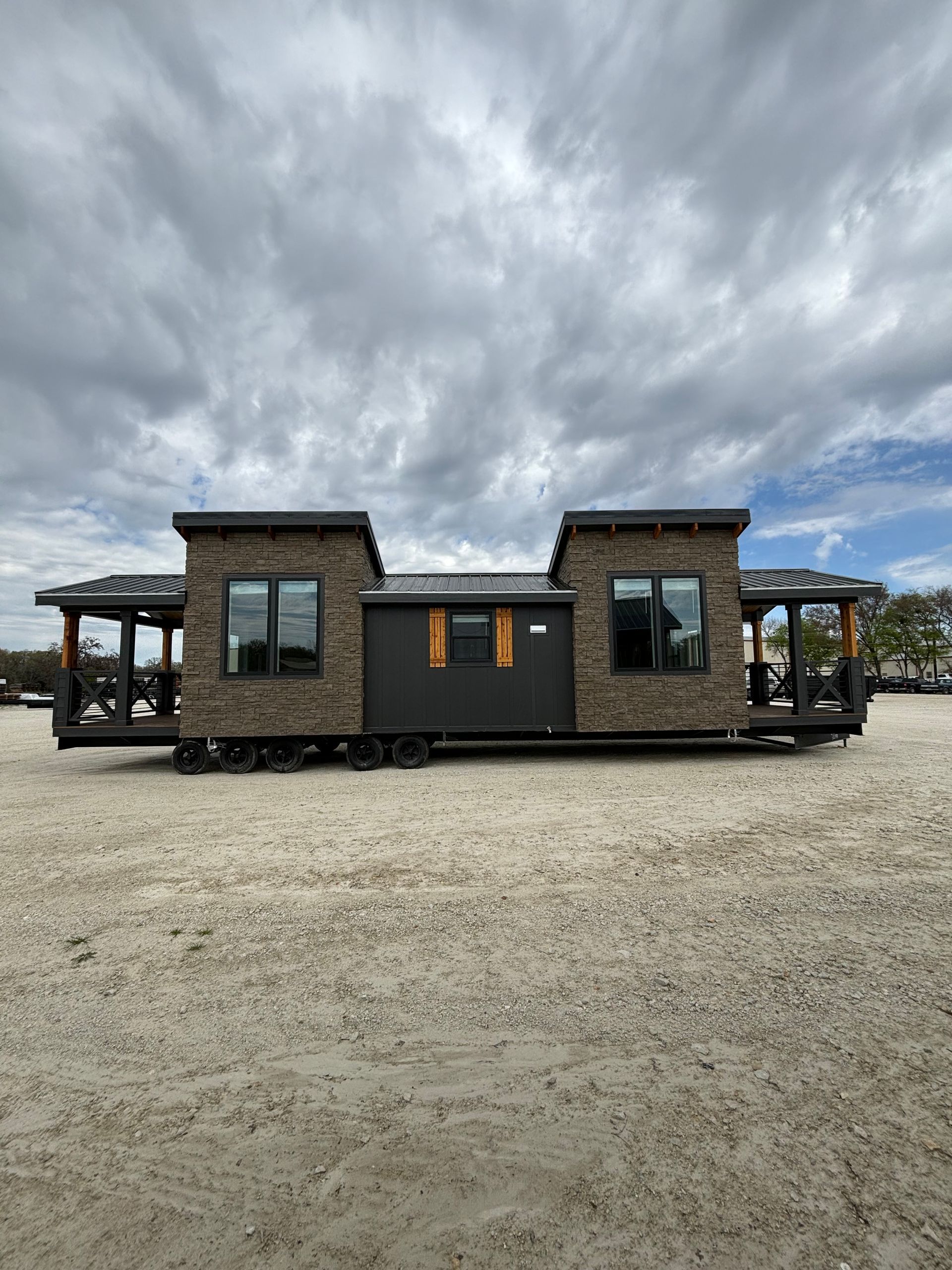 A brick house is sitting in the middle of a dirt field.