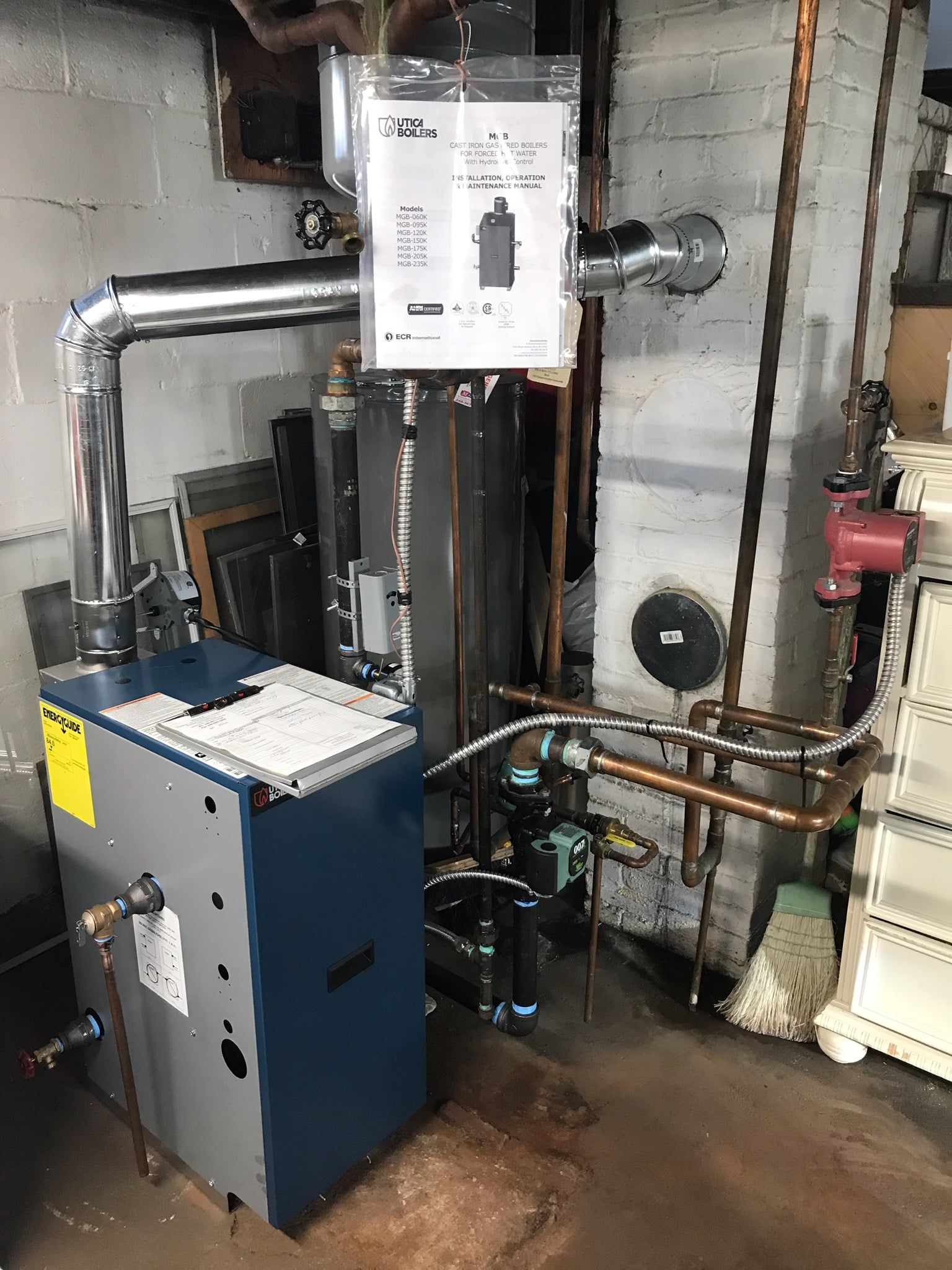 Basement utility room with boiler, pipes, and water heater against unfinished concrete walls