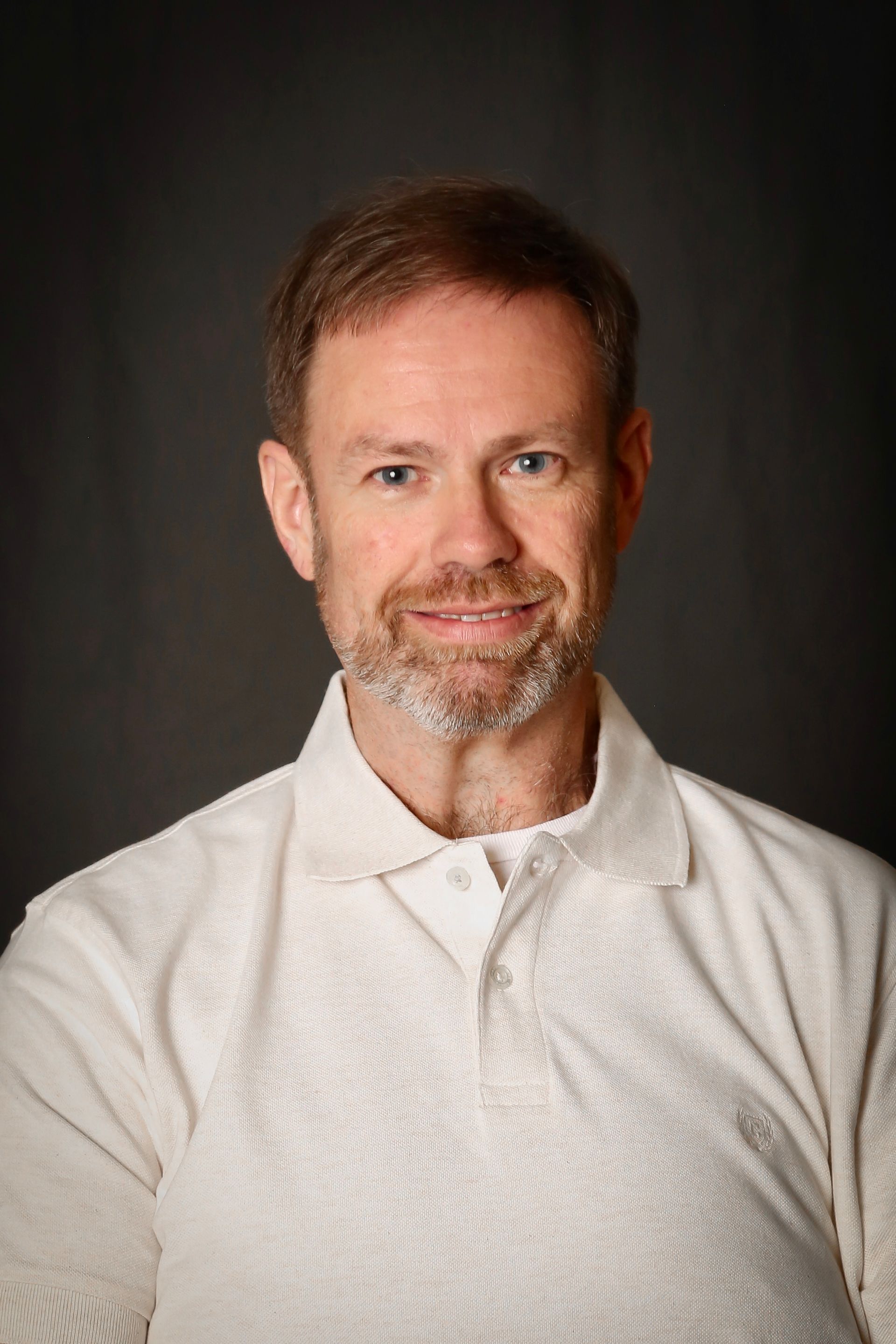 Couple smiling, woman in patterned top, man in suit with yellow bow tie, outdoors.