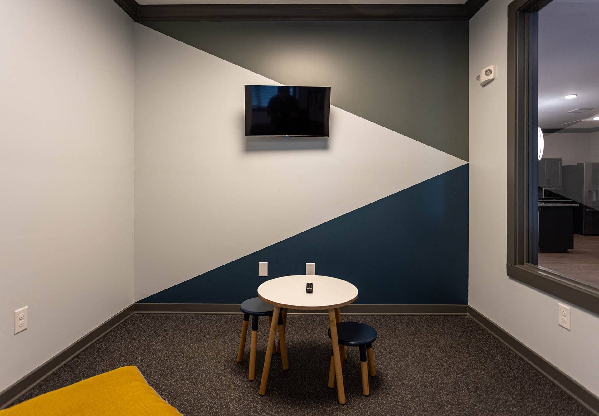 a small table and three stools sit in front of a blue and white wall with a