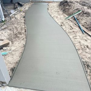 Freshly poured concrete walkway, curving through a dirt yard.