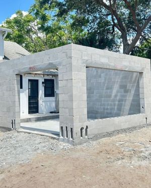 Excavator digging a rectangular hole in a backyard next to a house with a glass roof.