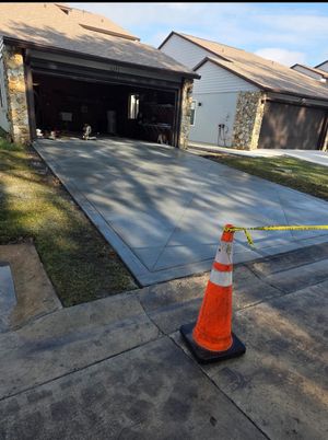 Newly poured concrete driveway with orange cone and caution tape.