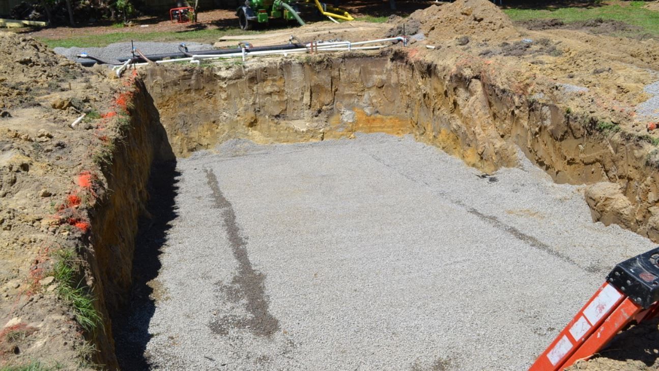 Excavated site with gravel base prepared for professional fiberglass pool installation