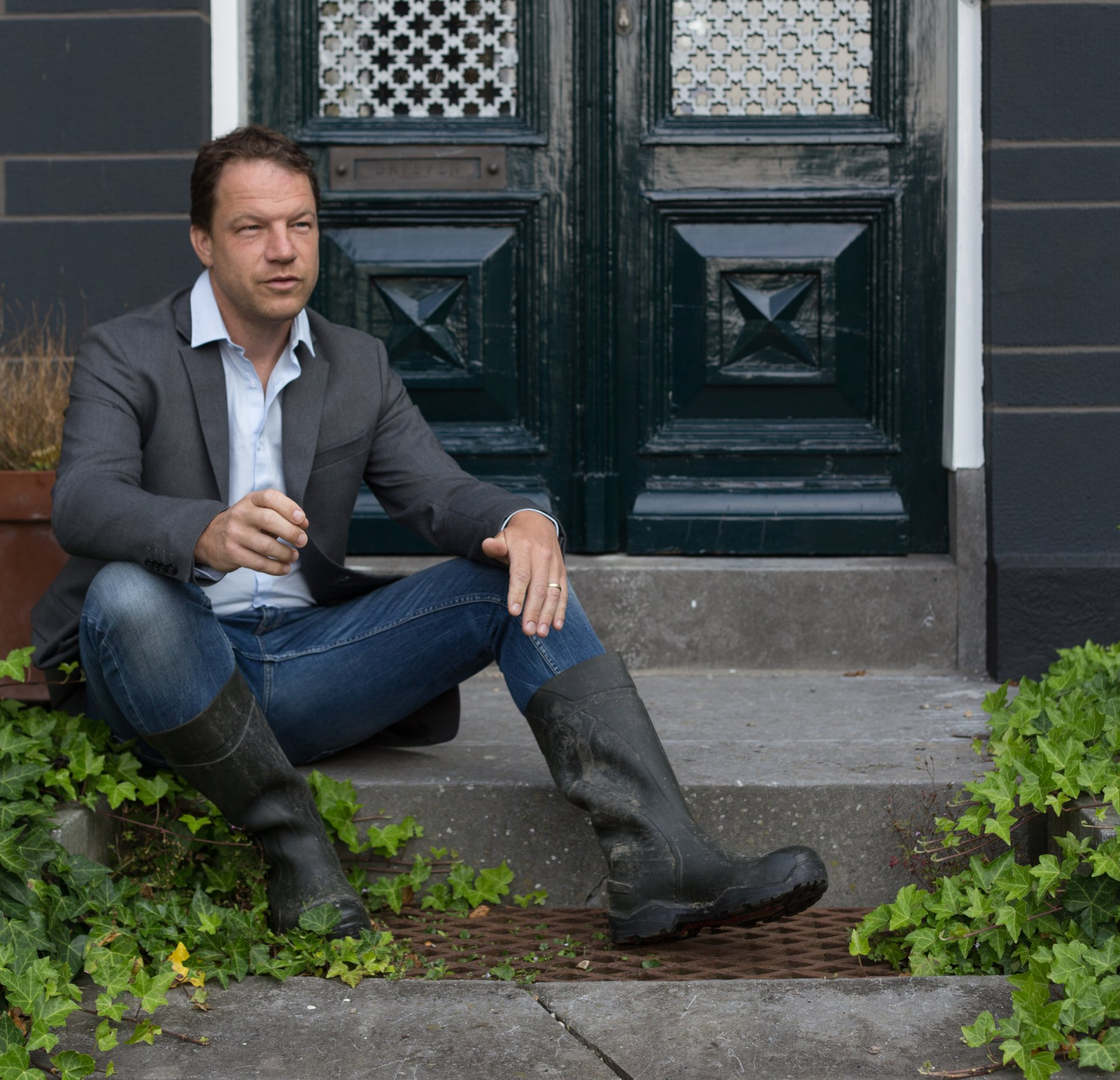 Christian Kolk van KTK Tuinontwerp en Groenadvies zit op de trap bij de voordeur van het herenhuis Oosterhouw in Leens