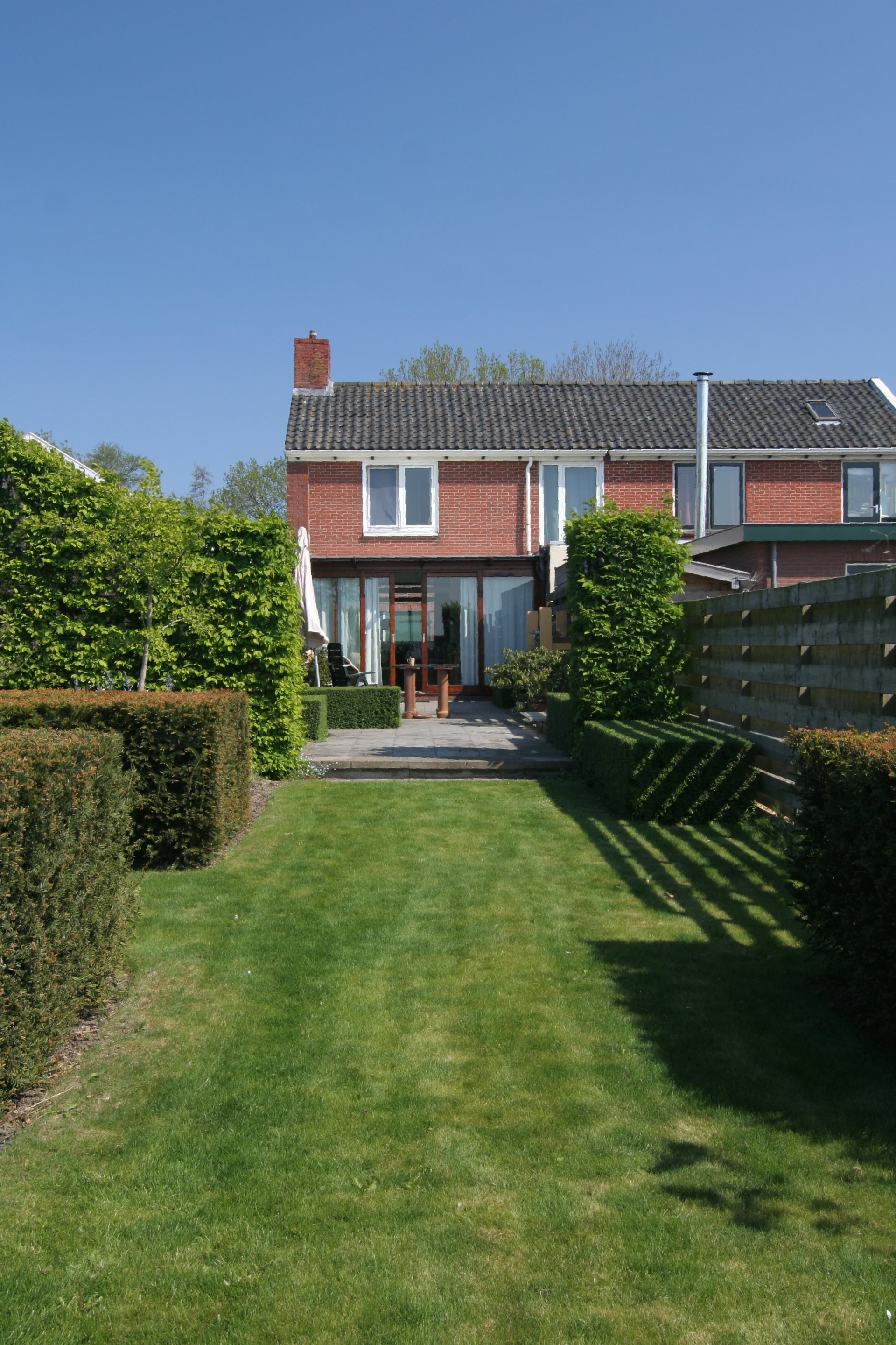 aanzicht achterkant huis in Molenrij met markante taxus blokken