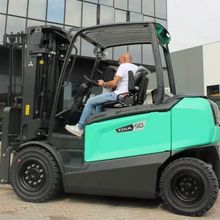Uomo alla guida di un carrello elevatore verde acqua e nero all'aperto.