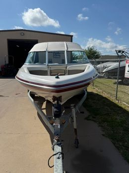White motorboat on a trailer outside a garage on a sunny day
