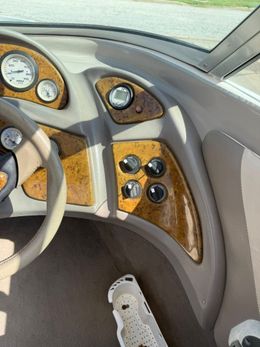 Car dashboard with wood trim, gauges, controls, and a white sneaker near the footwell.