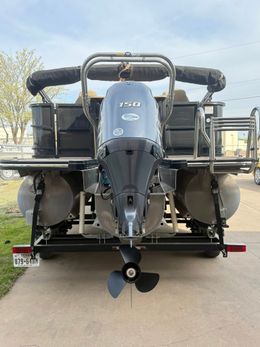 Front view of a gray multi-engine boat on a trailer, parked outdoors.