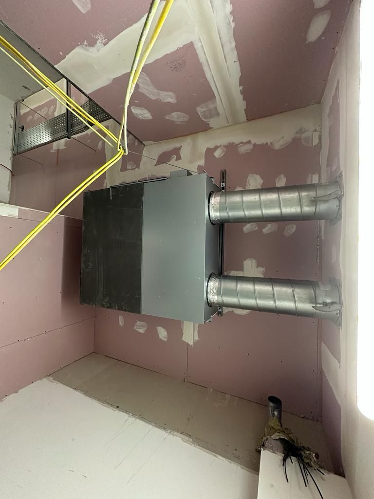 A room with pink walls and a metal box on the wall.