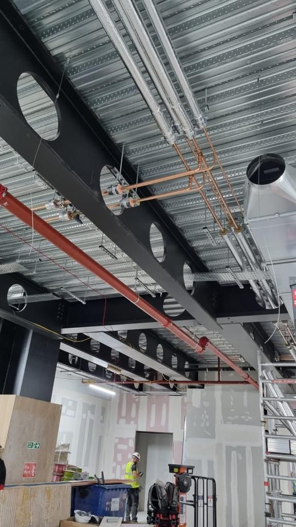 A building under construction with a lot of pipes hanging from the ceiling.
