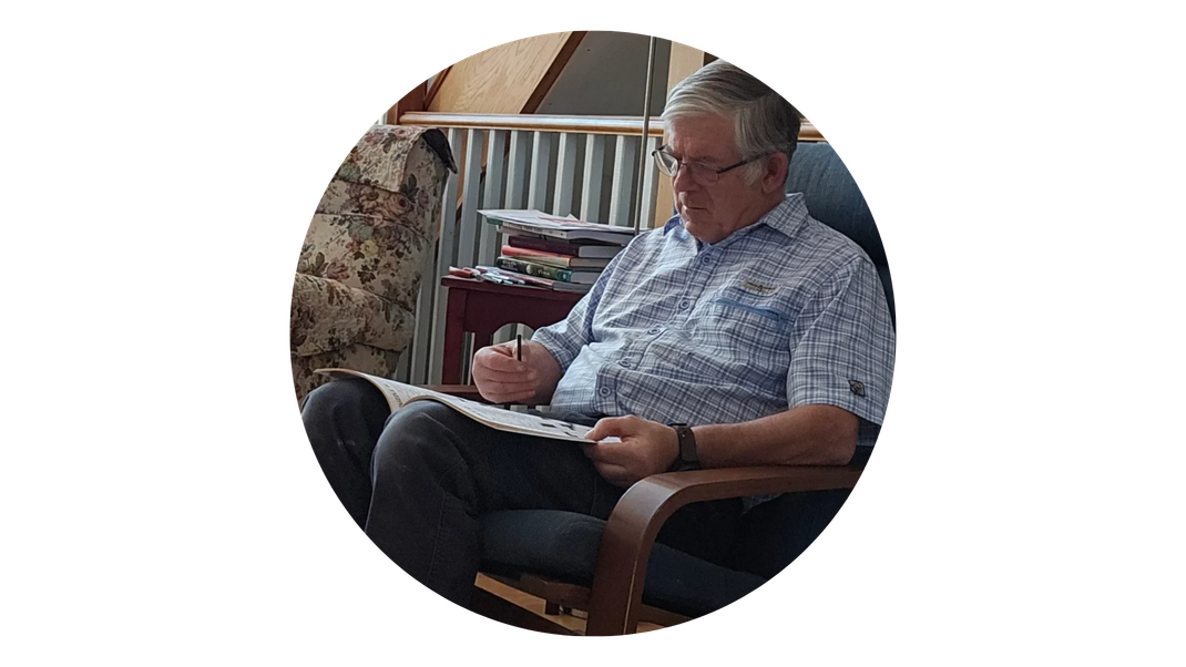 A man is sitting in a chair reading a newspaper.
