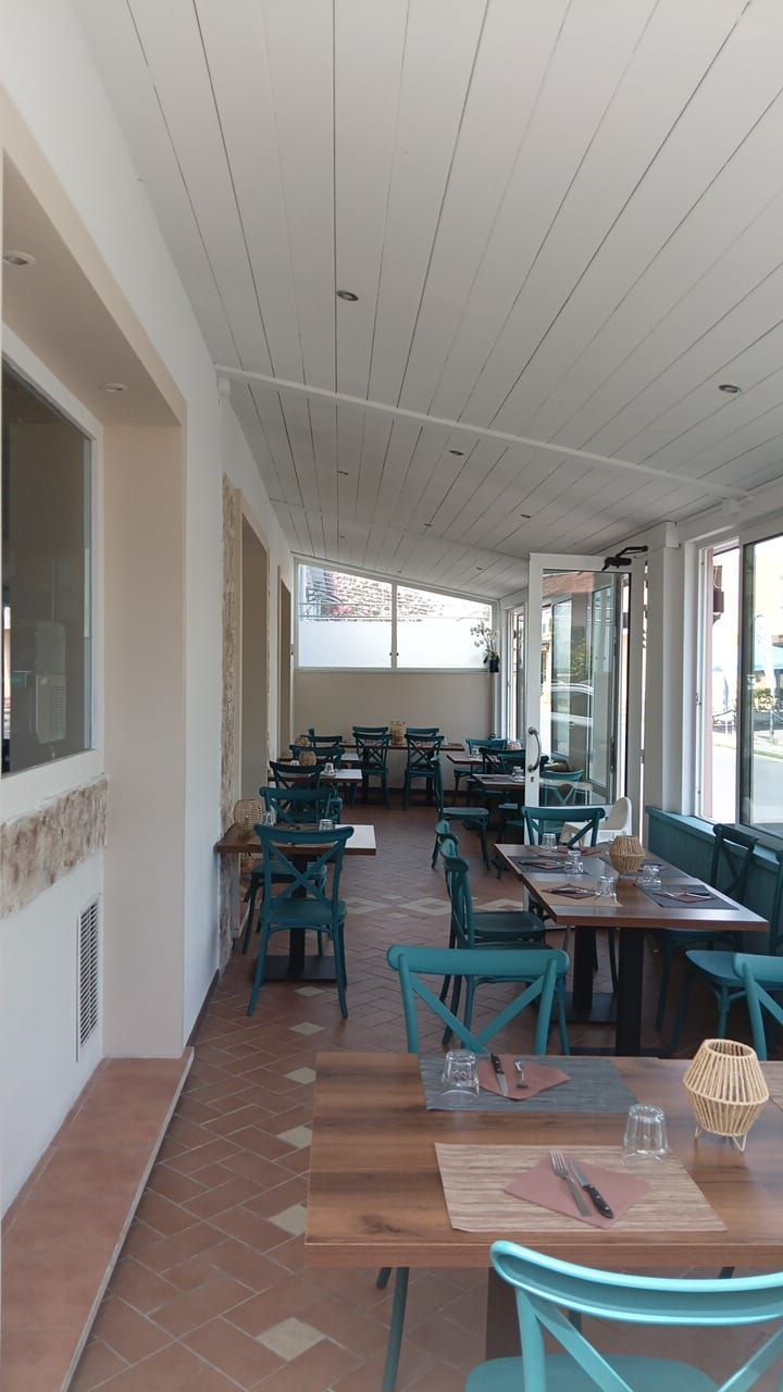 Un lungo corridoio con tavoli e sedie in un ristorante