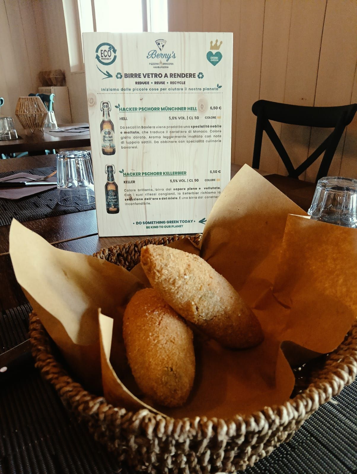 Un cestino di pane è appoggiato su un tavolo accanto a un menu