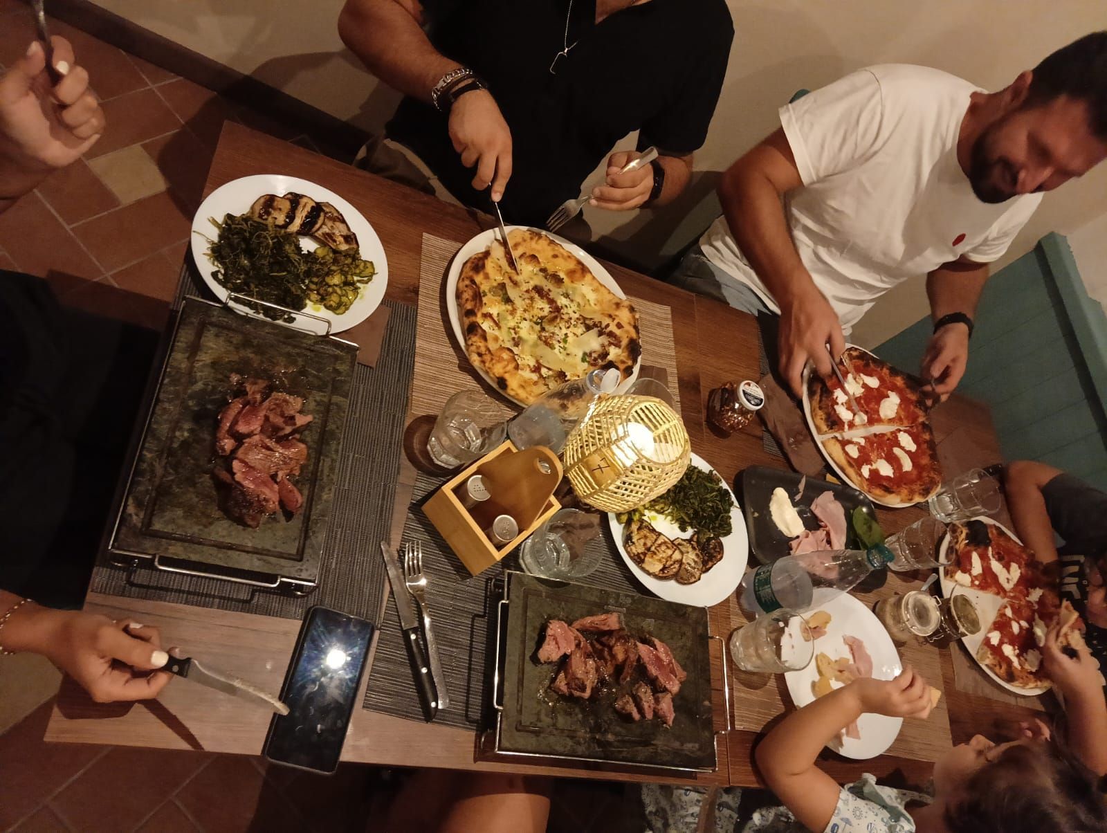 Un gruppo di persone è seduto a un tavolo e mangia la pizza
