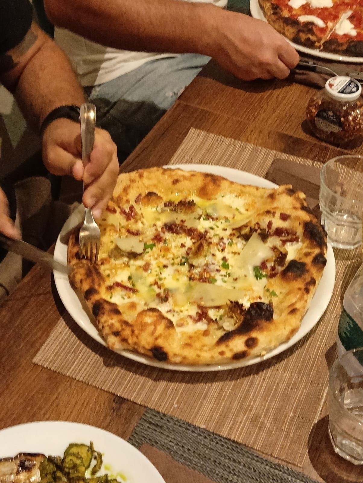 Una persona sta tagliando una pizza con una forchetta