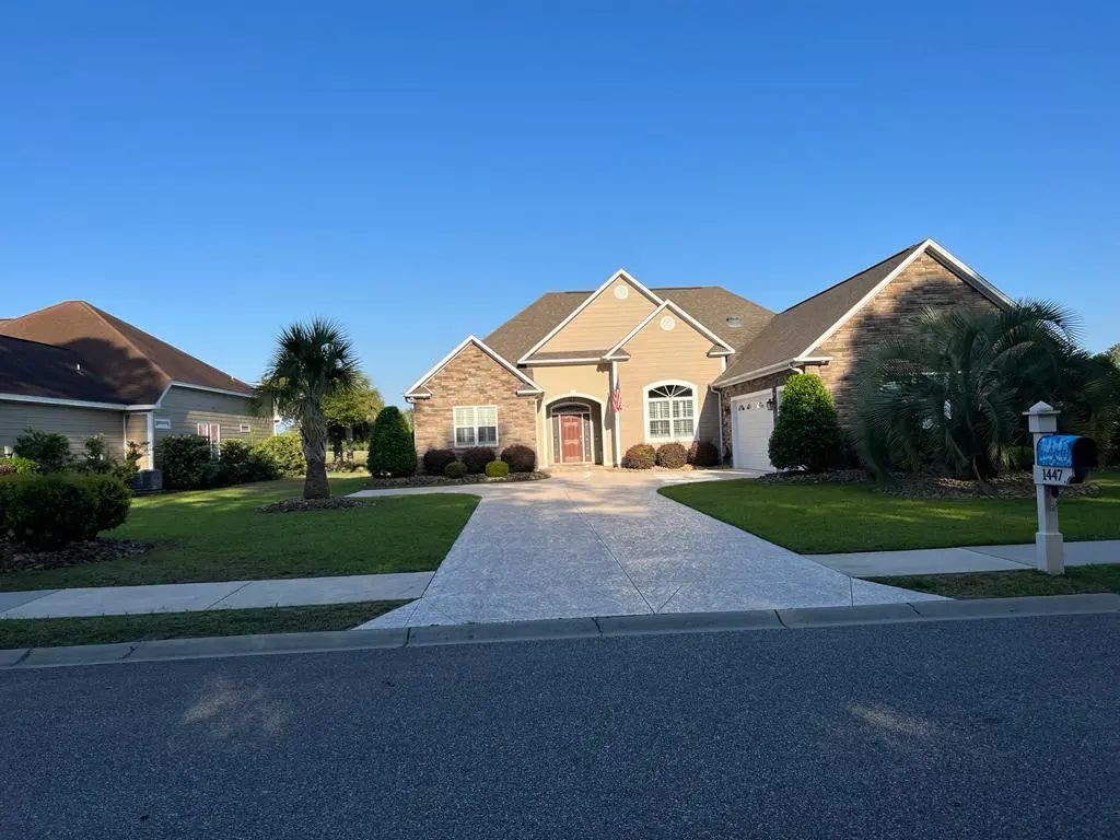 House with stone facade and driveway; blue sky overhead.