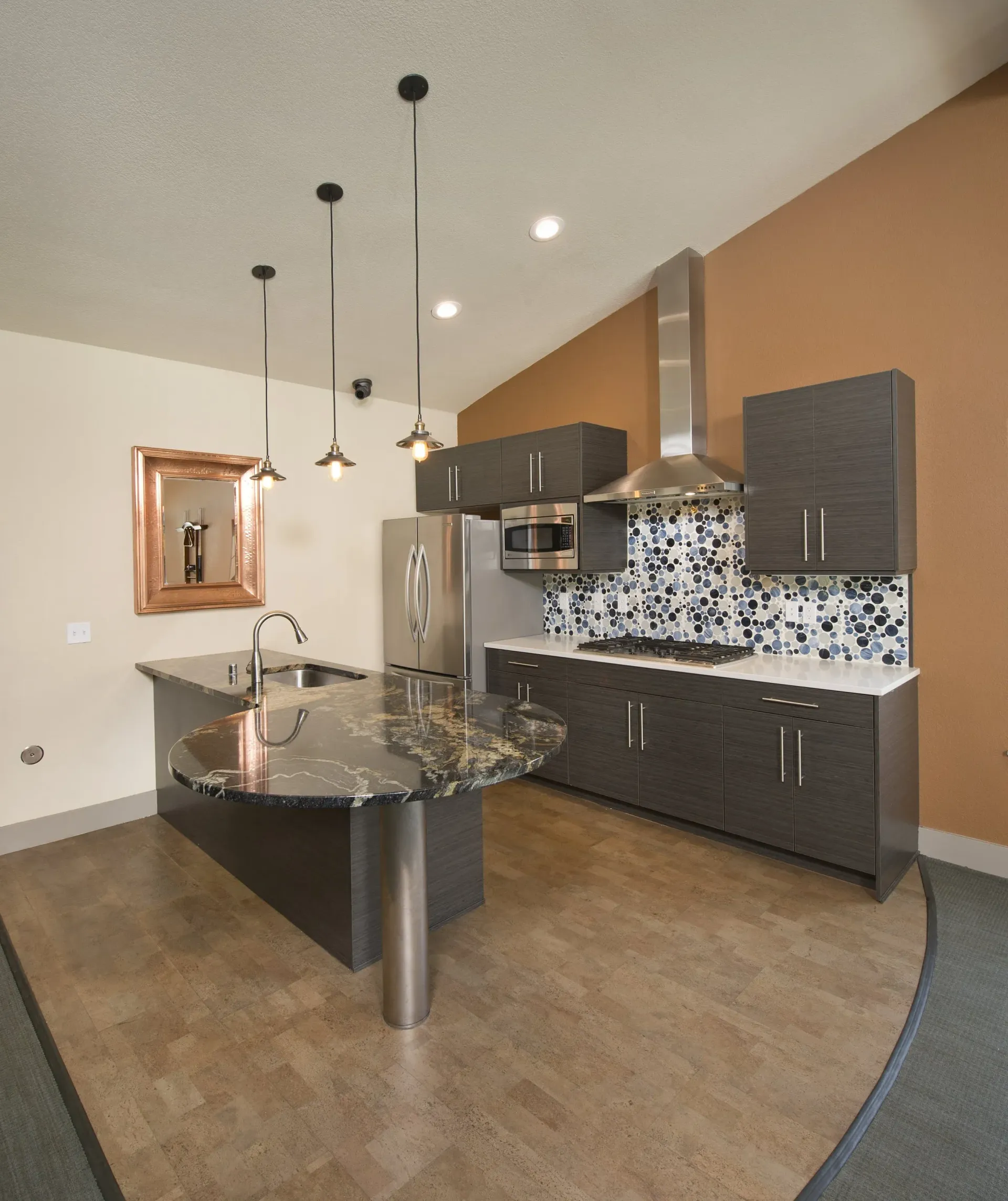 Kitchen in a modern apartment with dark wood cabinets, stainless appliances, and a curved marble island.