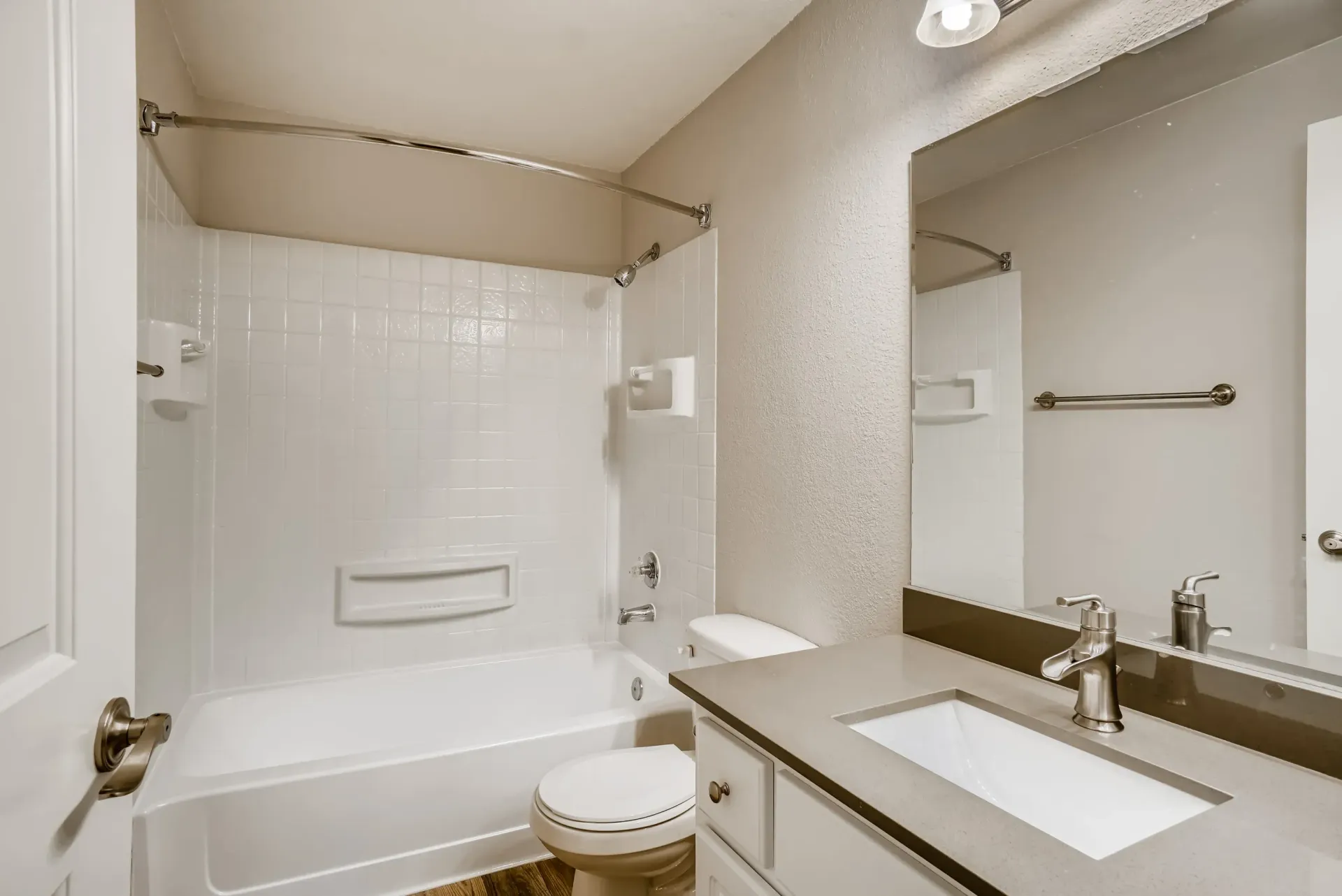 Bathroom with white tile shower/tub, toilet, and vanity.