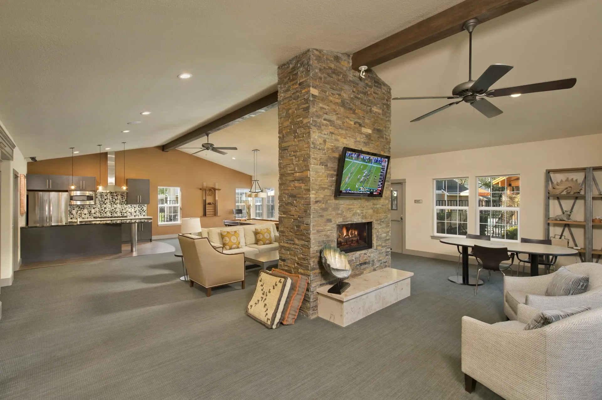Spacious communal lounge with a stone fireplace, seating, and a wall-mounted TV.