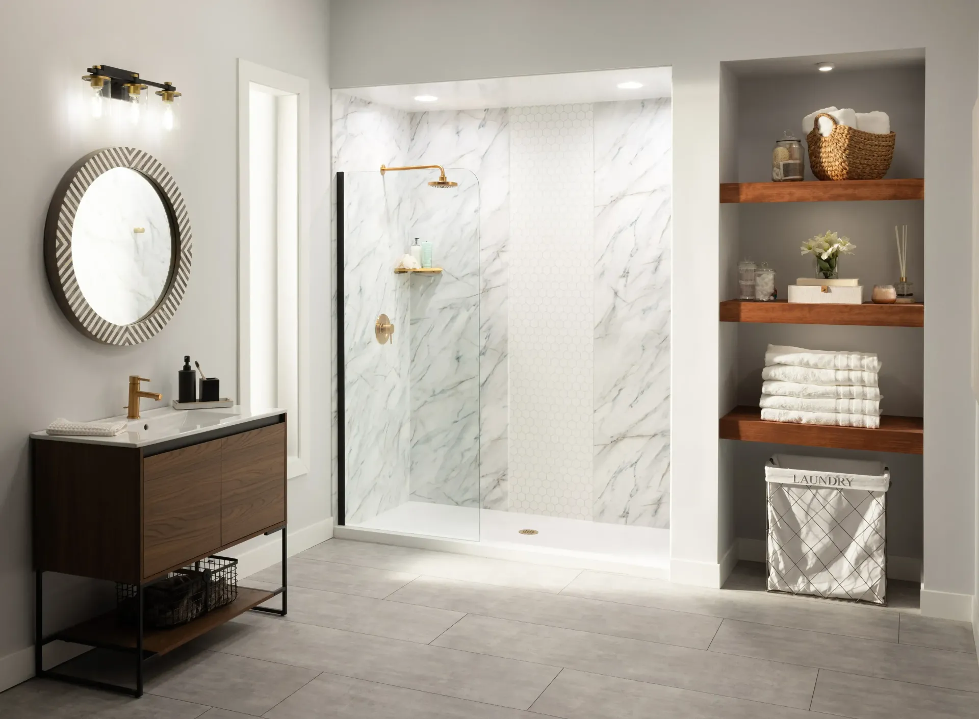 Modern bathroom with glass shower, wood vanity, round mirror, and built-in shelves with towels and decor.