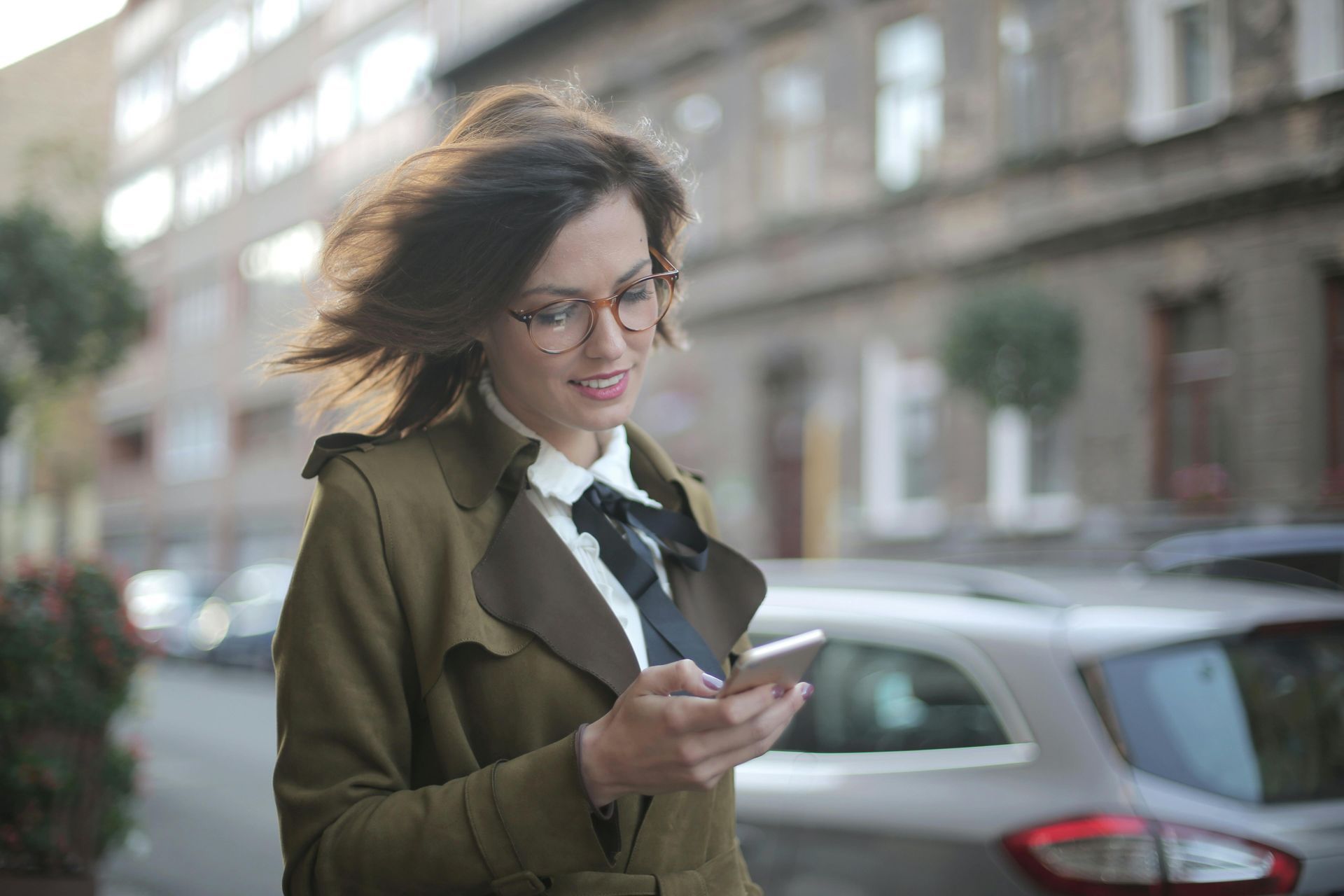 Una mujer camina por la calle mientras mira su teléfono celular.