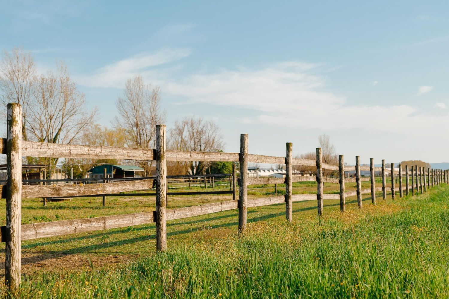 There is a wooden fence in the middle of a grassy field.