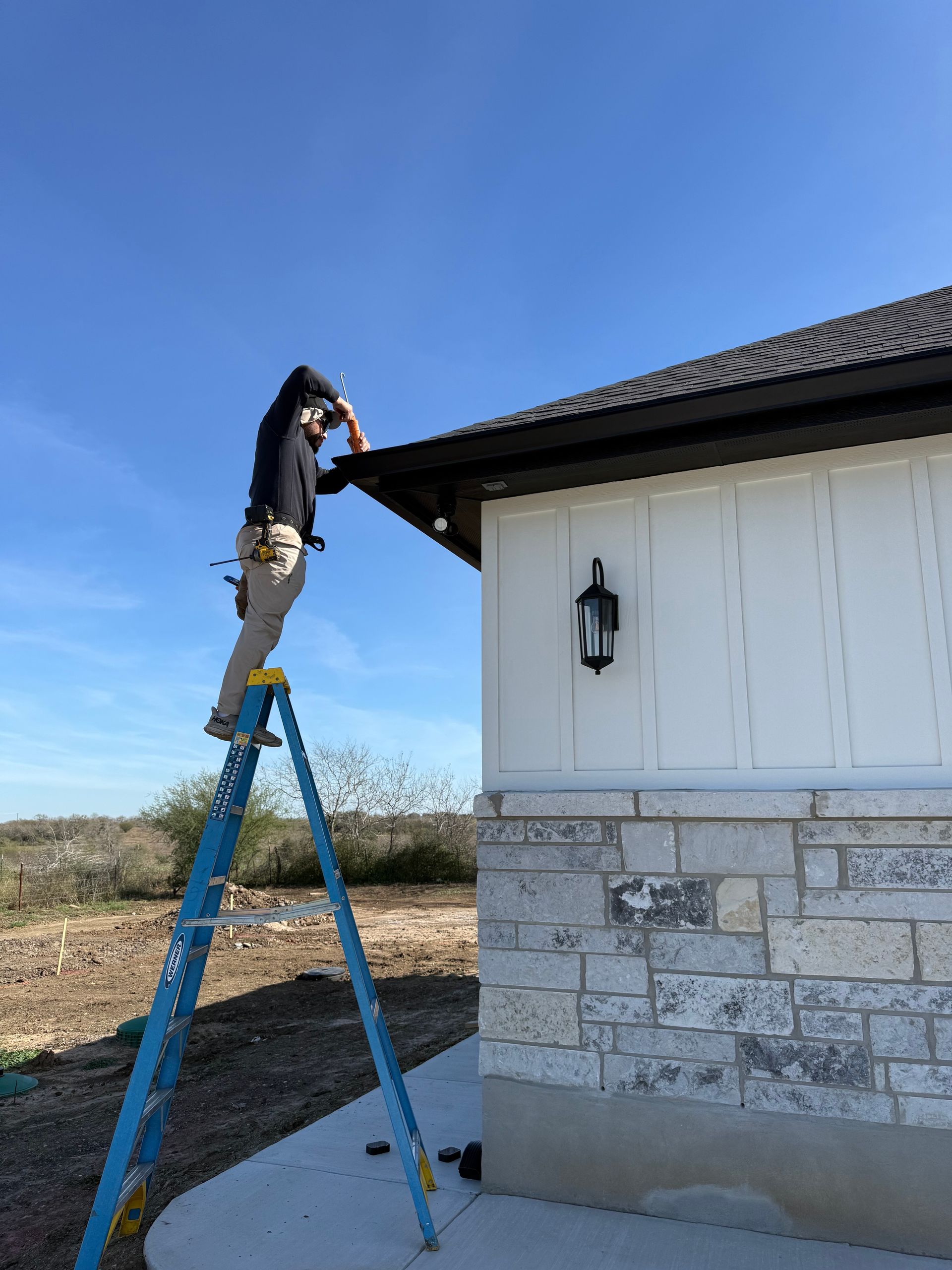 Roofer in red shirt working on a house roof. Pink insulation and other roofing materials visible.