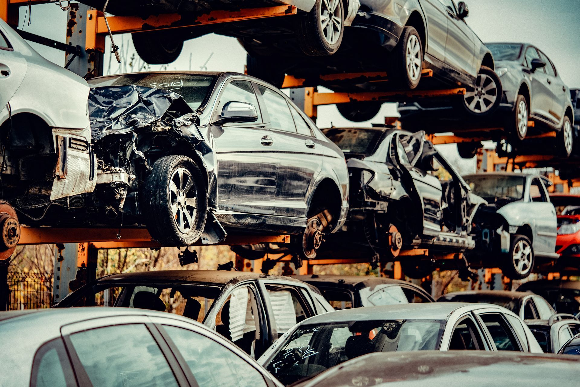 Stacked salvaged vehicles at an automotive scrap yard awaiting processing and metal recycling