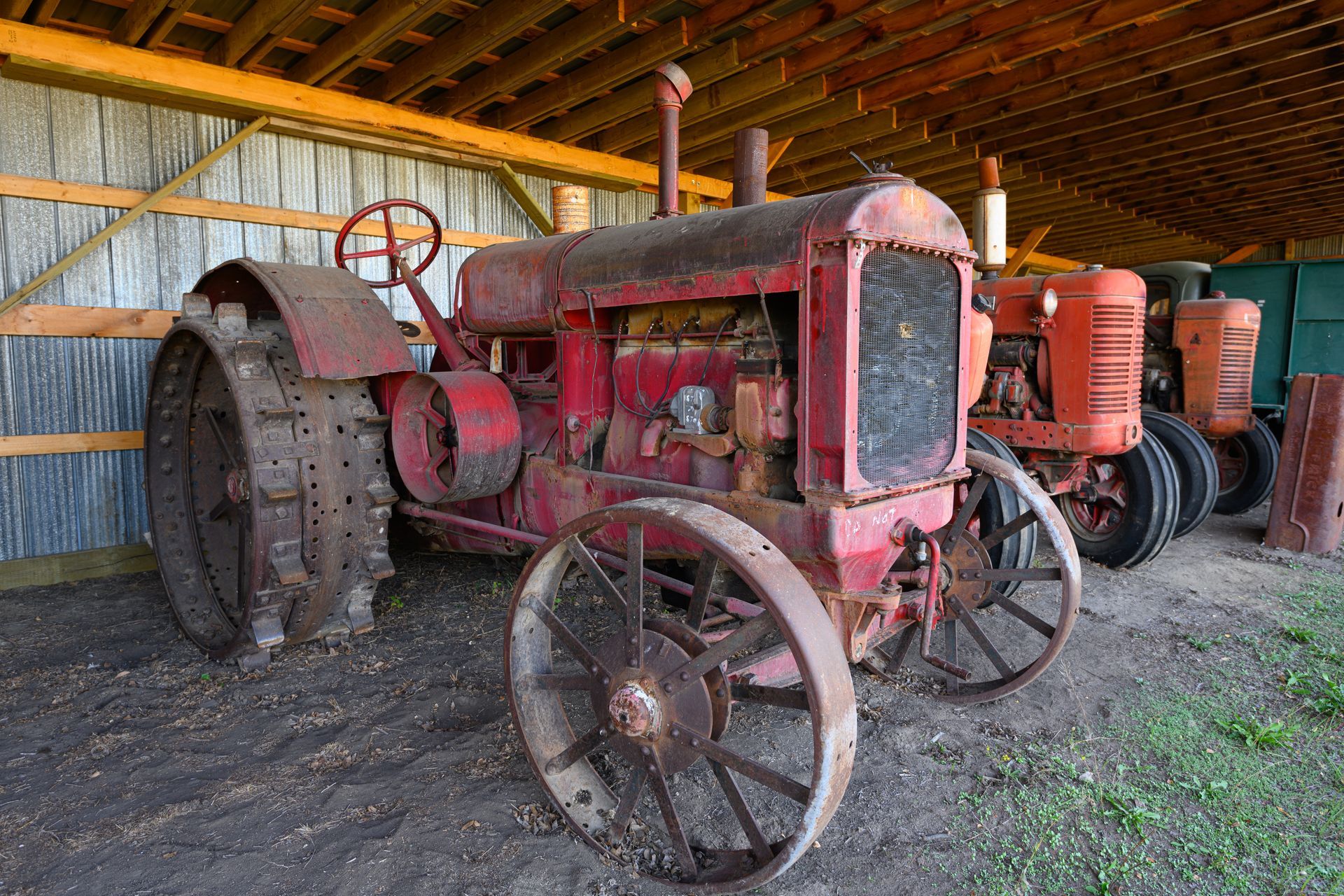 Rusted vintage tractors stored in a farm shed awaiting salvage or agricultural scrap metal recycling