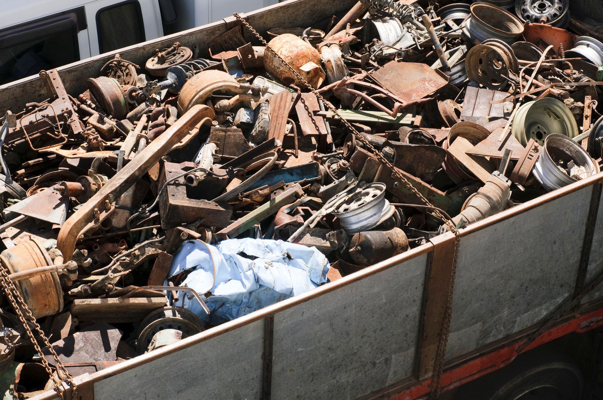 A box filled with junk is being loaded onto a trailer, highlighting a scrap metal recycling box.