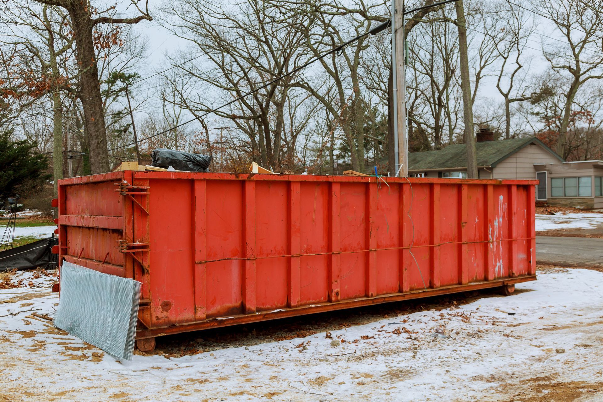 A red commercial roll-off container in the snow, located in Chicago, IL, by Big Daddy Scrap.