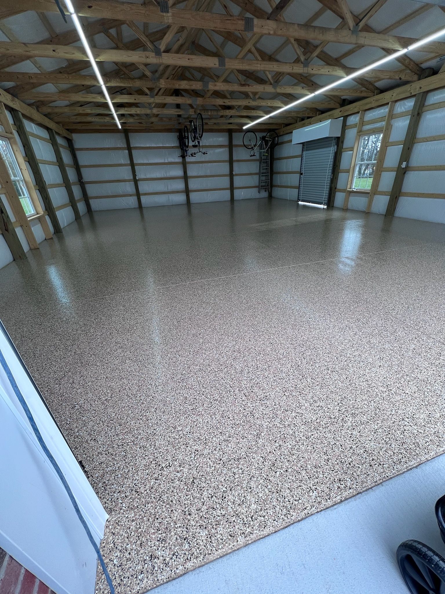 Interior of a garage with a speckled epoxy floor and wooden beams.