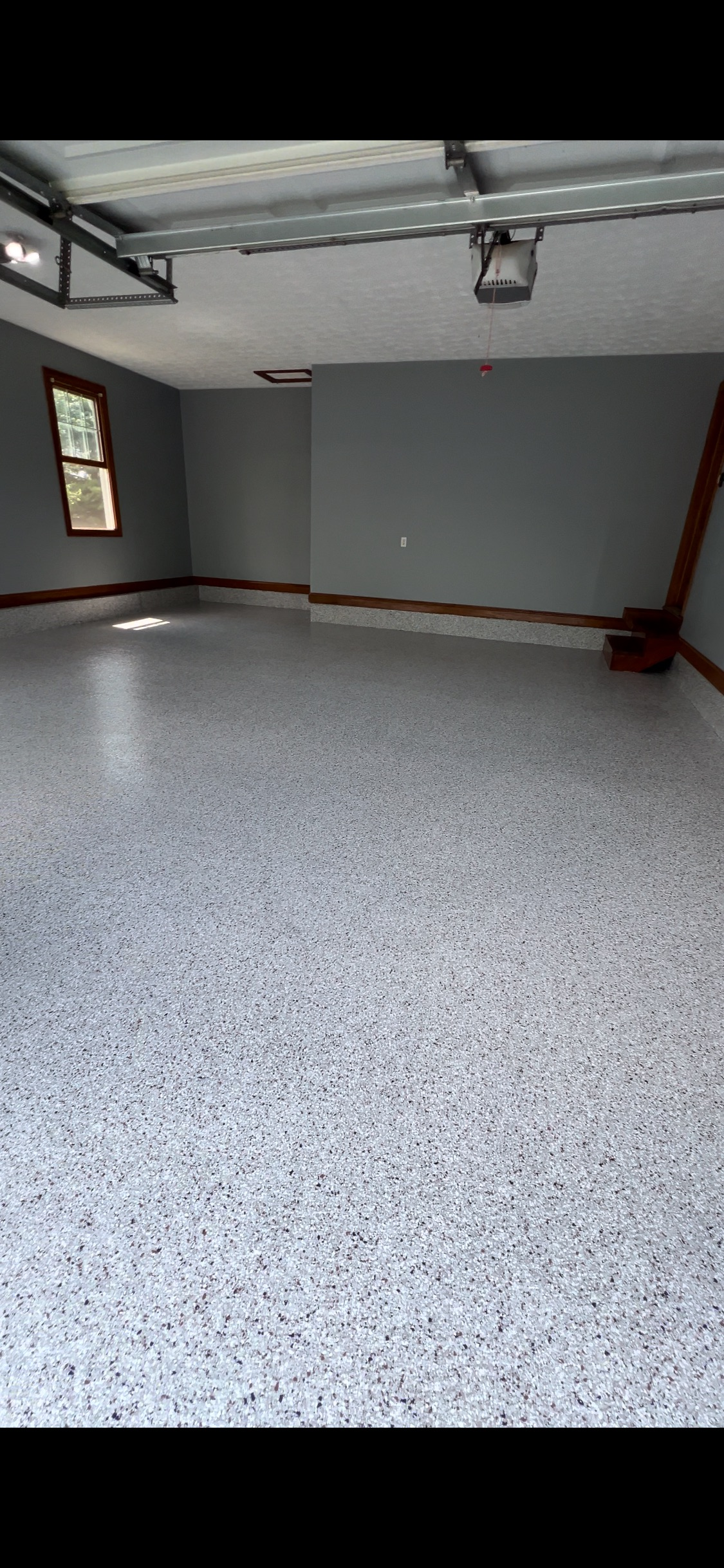 Empty garage with a speckled epoxy floor and gray walls.