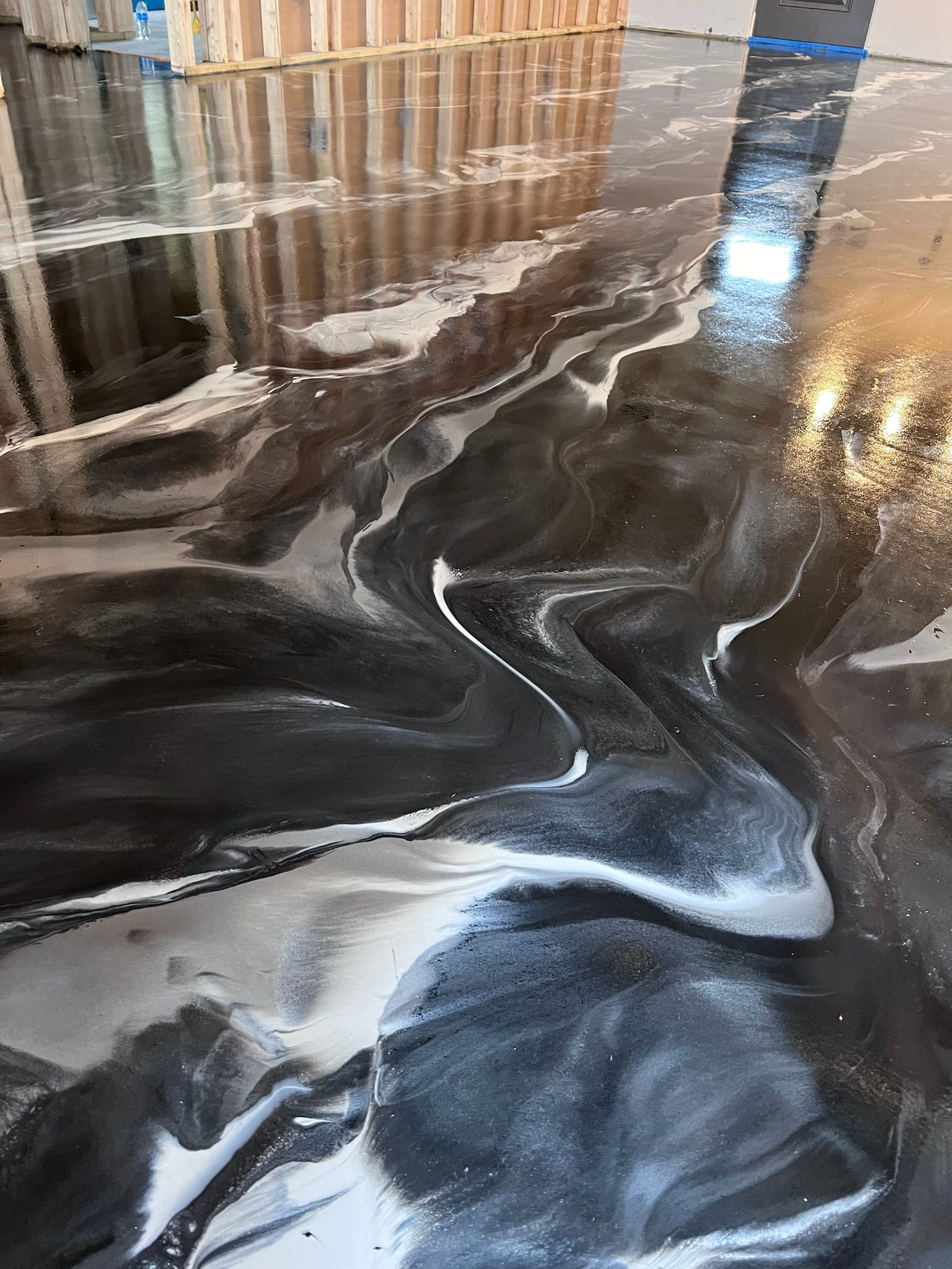 Swirling, metallic epoxy floor with black and silver marbling; indoors.