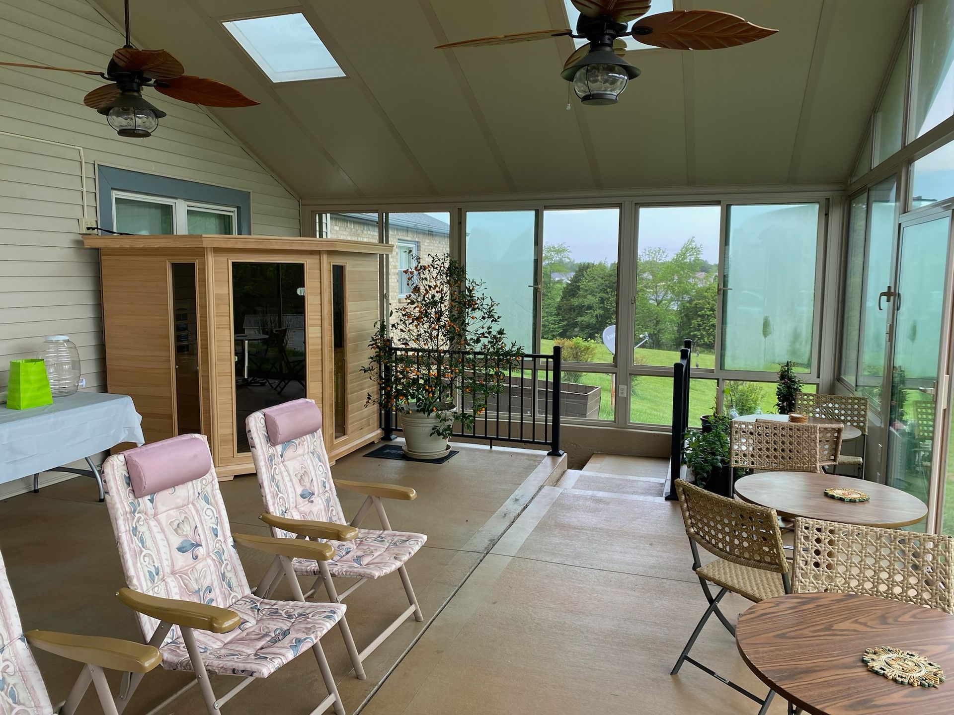 Sunroom with a sauna, seating, and a view of green space.