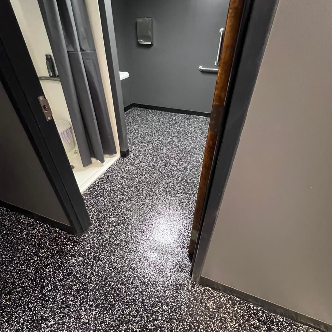 Bathroom with dark walls, speckled floor, and a shower stall with gray curtain.